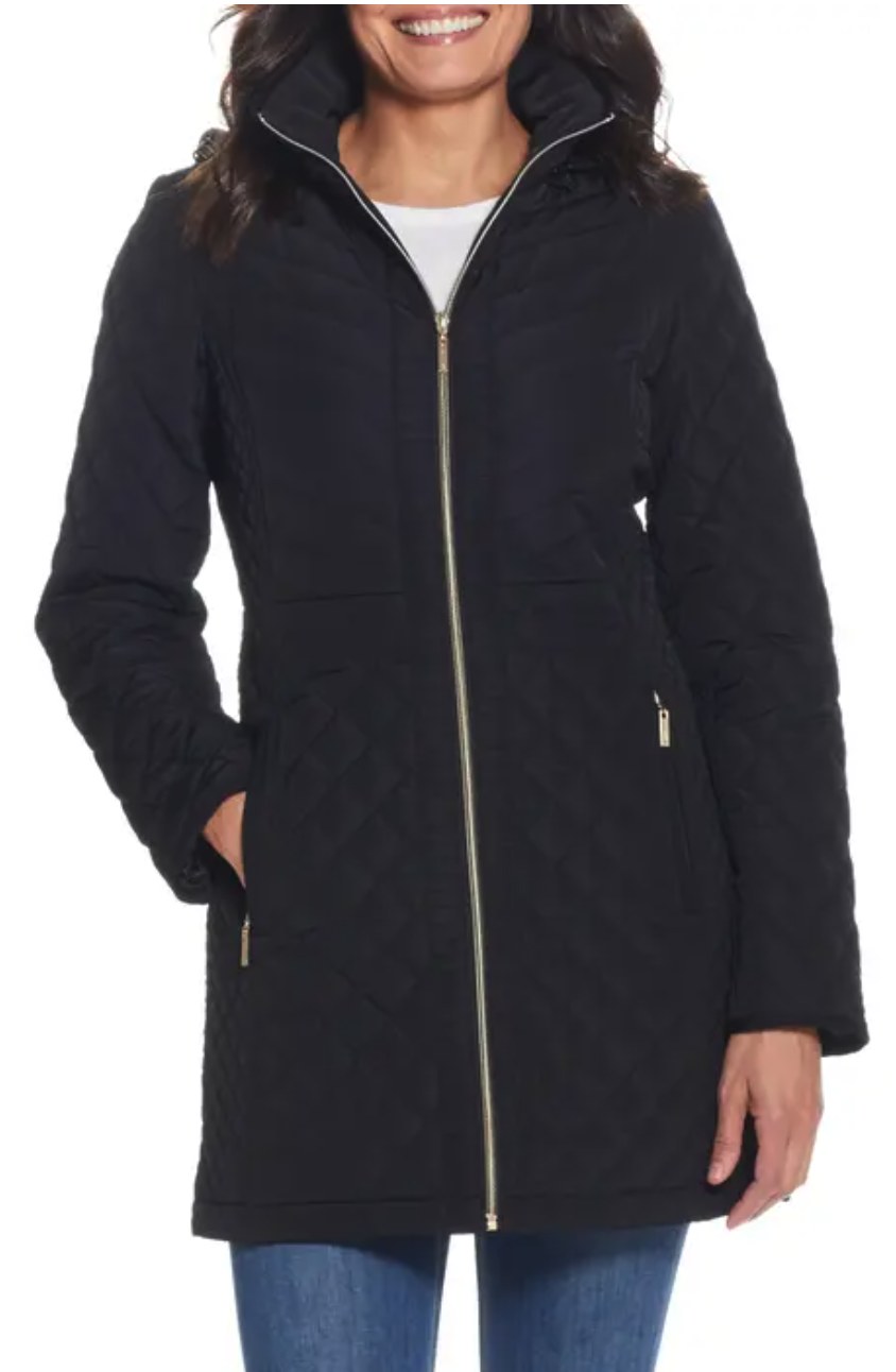 Woman wearing a black quilted mid-length coat with gold zipper and high neck collar
